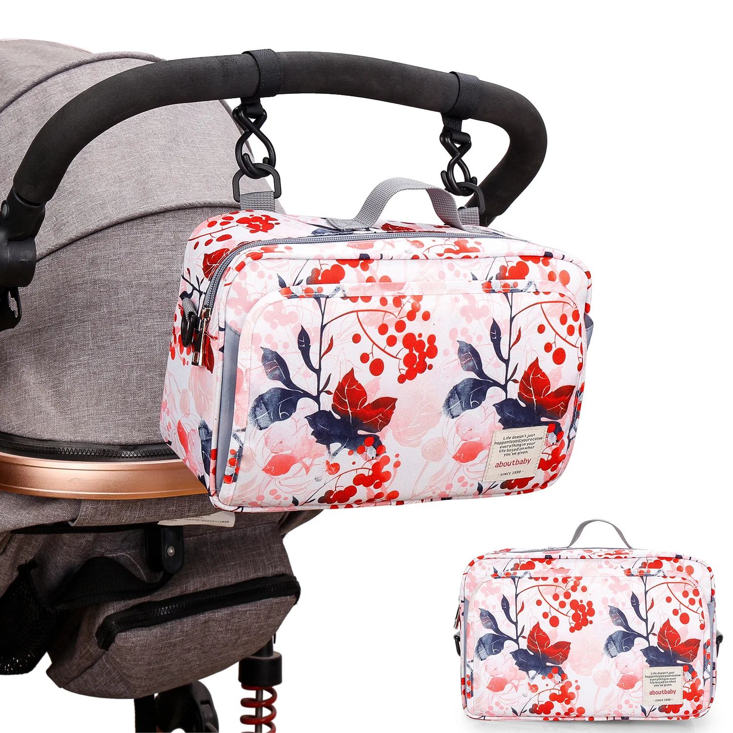 Un cochecito de bebé con un bolso con estampado floral sujeto al asa. La bolsa parece ser una bolsa de pañales, diseñada para contener elementos esenciales para un bebé, como pañales, toallitas y biberones.