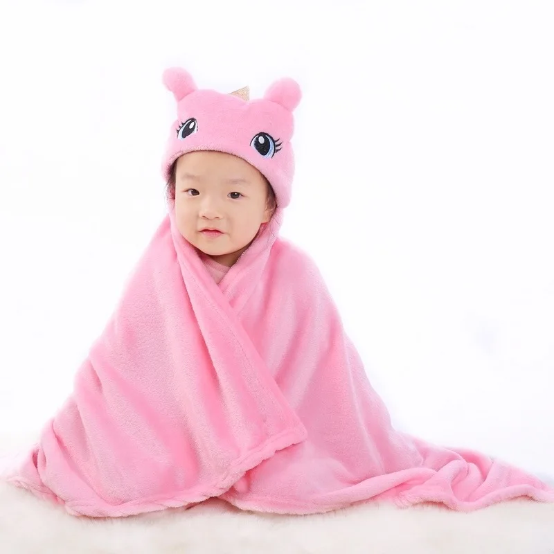 Un niño pequeño con un sombrero rosa con un lindo diseño de cara de animal, posiblemente un gato o un conejito, y envuelto en una manta rosa