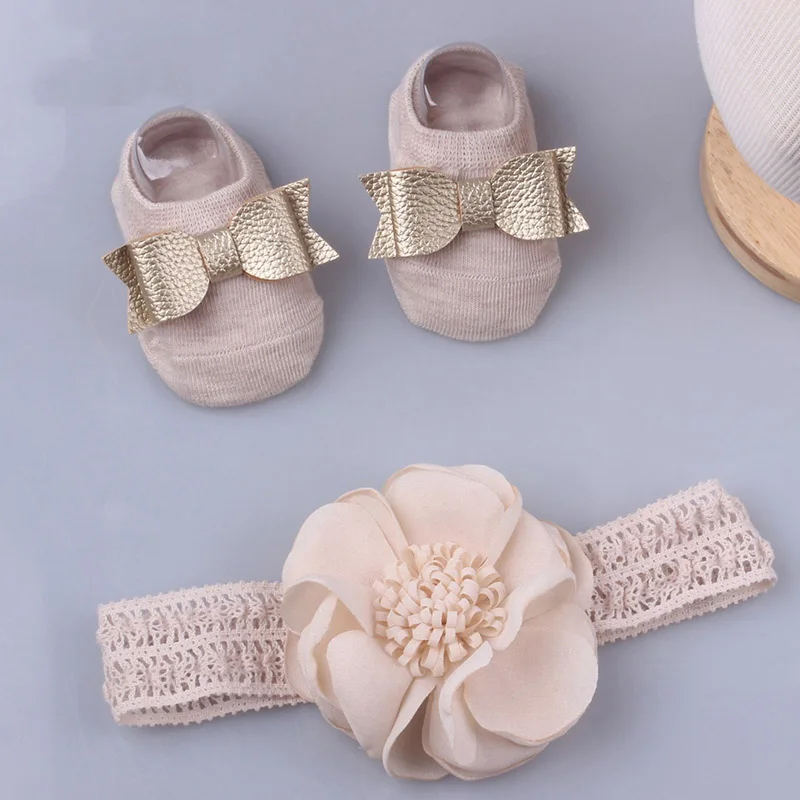 Un par de zapatos de bebé con arcos y una flor en un encaje