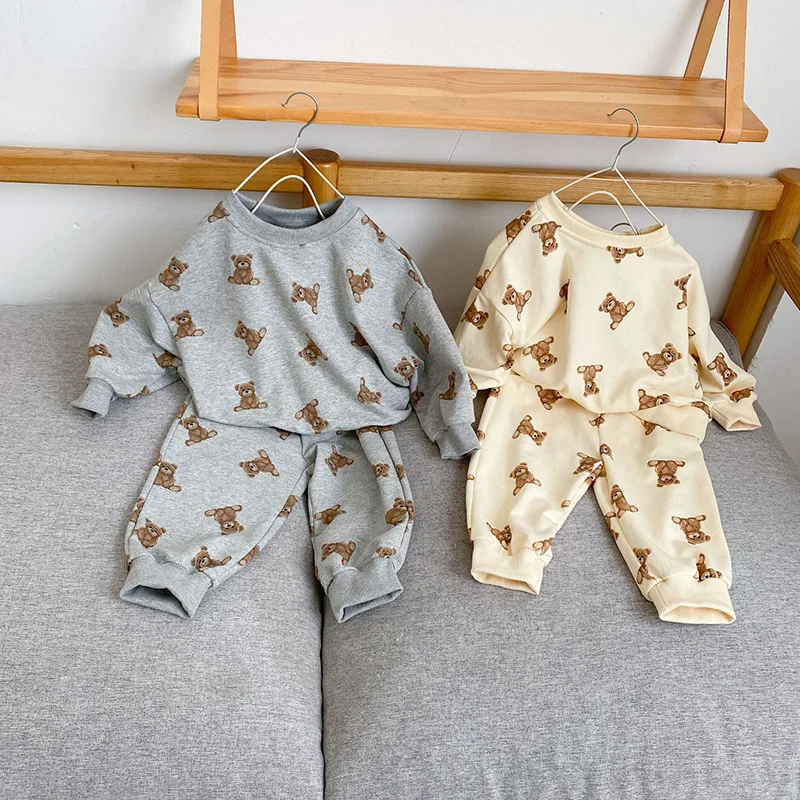 Dos atuendos para bebés colgando de una rejilla de madera