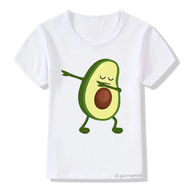 Una camiseta blanca con el gráfico de un personaje de aguacate. El aguacate está antropomorfizado con brazos y piernas, y parece estar en una pose juguetona, posiblemente bailando o haciendo un gesto de shaka con una mano.