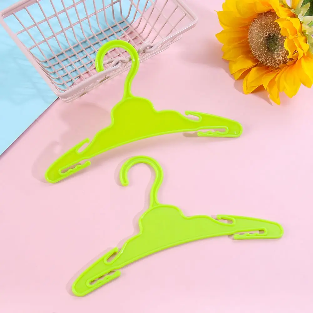 Dos perchas de plástico verde sobre un fondo rosa