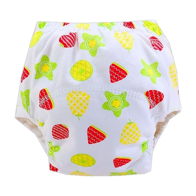 Un par de ropa interior infantil con un estampado de colores. El patrón incluye varias frutas como fresas, piñas y posiblemente otras frutas tropicales, junto con algunas hojas o estrellas verdes. La ropa interior es predominantemente blanca con diseños de frutas en colores rojo, amarillo y verde.