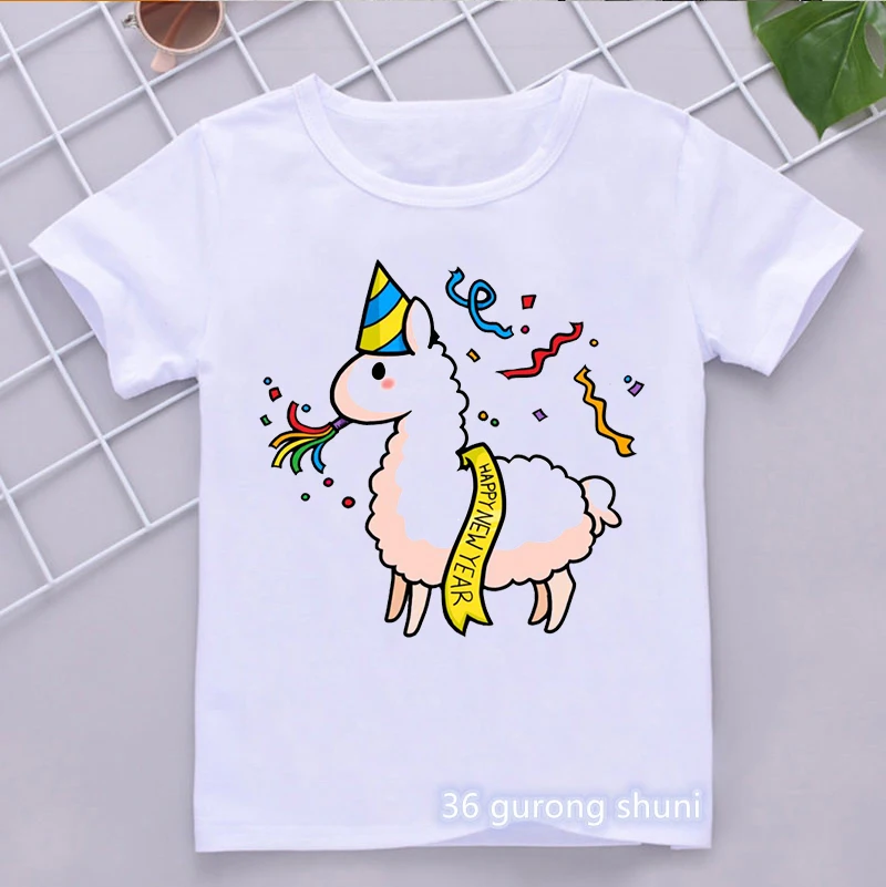 Una camiseta blanca con un diseño gráfico. El diseño presenta una representación de estilo de dibujos animados de una llama con un sombrero de fiesta y tocando un cuerno de fiesta. La llama también lleva una pancarta que dice Feliz Año Nuevo.