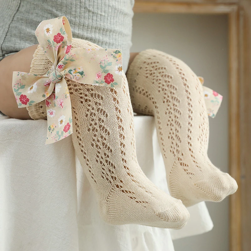 Un par de calcetines para bebés con un patrón de flores y un arco