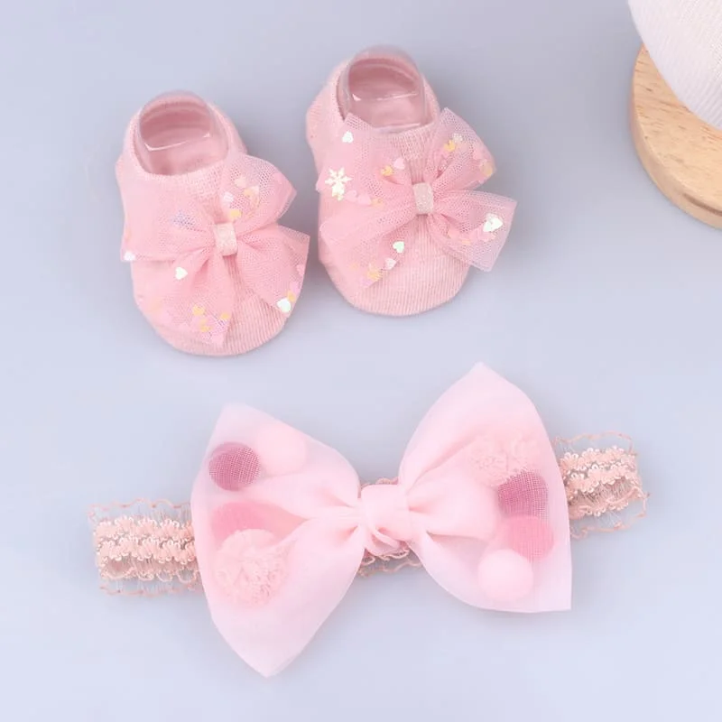 Un par de zapatos de bebé rosa con arcos y una pajarita rosa