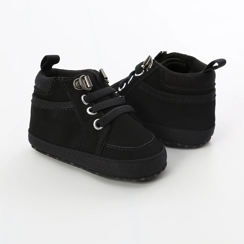 Un zapato negro de bebé con una hebilla plateada