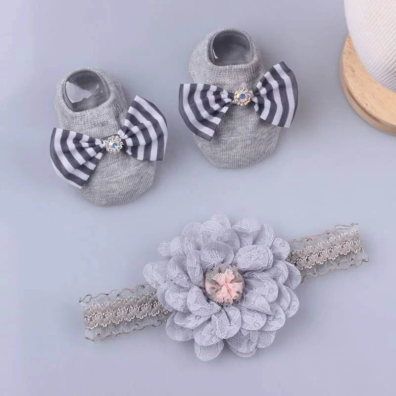 Un par de zapatos de bebé con arcos y una flor en una diadema de encaje