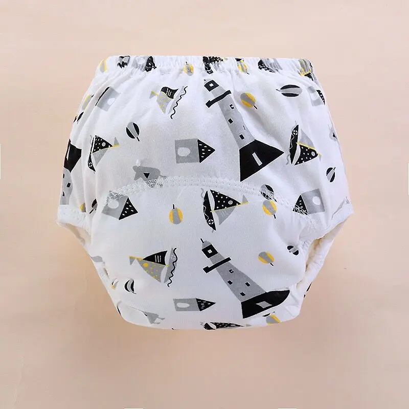 Un pañal con un estampado de formas geométricas y lo que parece ser una temática náutica, que incluye elementos como anclas y aros salvavidas. El pañal es predominantemente blanco con detalles en negro y amarillo.