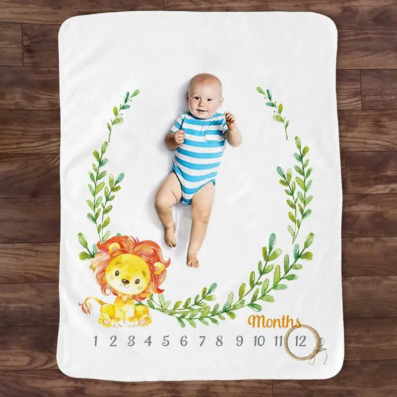 Un bebé acostado sobre una manta blanca con un diseño colorido. El diseño incluye un león estilo caricatura y algo de vegetación, posiblemente hojas o ramas.