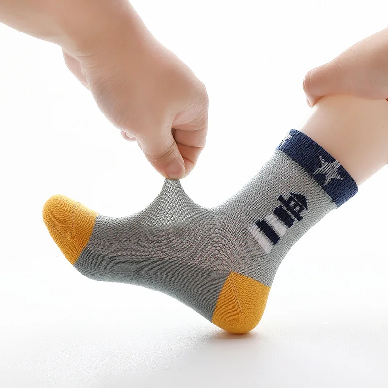 Se pone un par de calcetines en el pie de una persona. Los calcetines tienen un diseño colorido con una mezcla de gris, amarillo y azul, y parece haber un patrón o logotipo en el lateral.