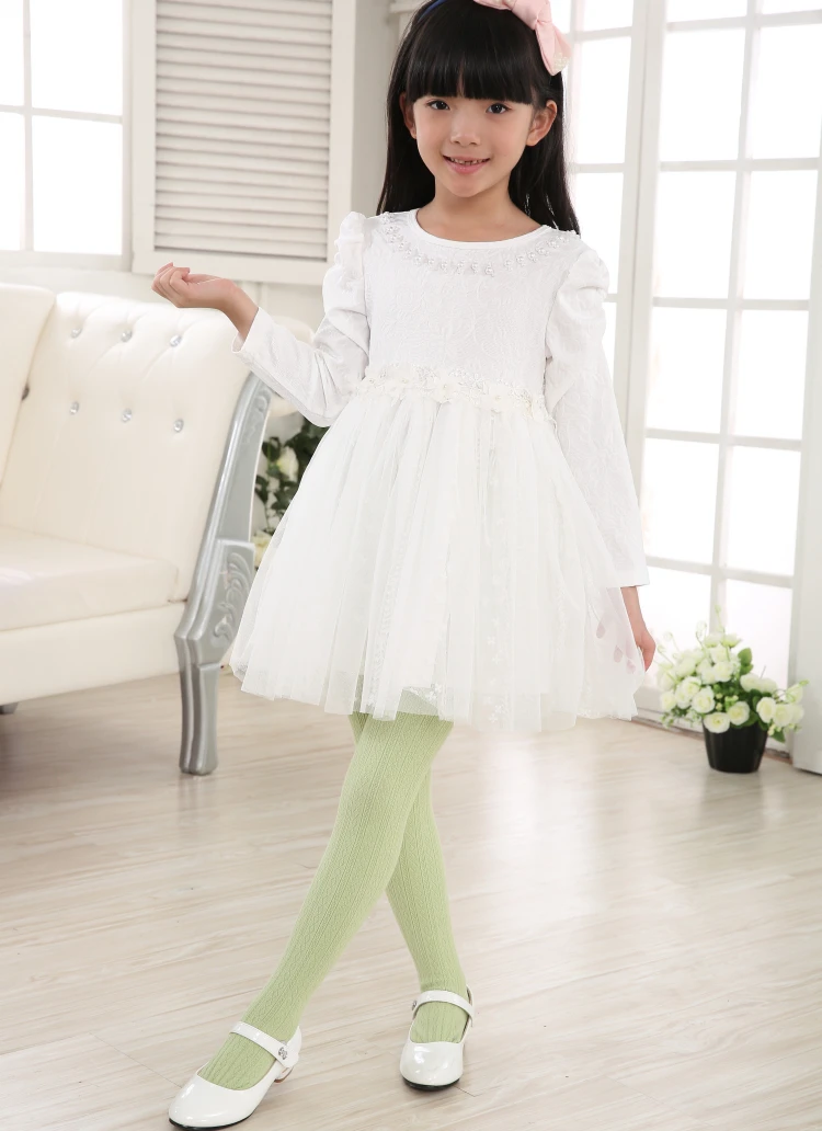 Una niña con un vestido blanco y medias verdes poses para una foto