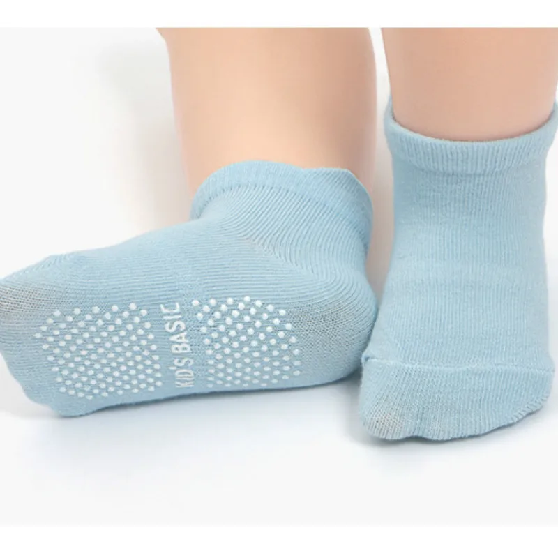 Un par de calcetines de color azul claro. Parecen estar diseñados para niños, como indica el texto KIDS BASIC en el calcetín. Los calcetines tienen un patrón acanalado y una zona reforzada en la puntera y el talón, lo cual es común en calcetines diseñados para brindar durabilidad y comodidad.