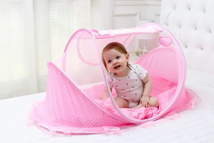 Un bebé sentado en un Playpen rosa