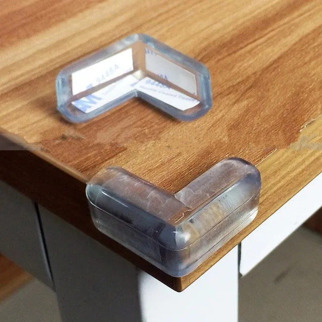 Un par de clips o soportes de plástico transparente, que parecen estar diseñados para guardar objetos pequeños como tarjetas de visita o tarjetas de identificación. Están apoyados sobre una superficie de madera, posiblemente una mesa o escritorio.