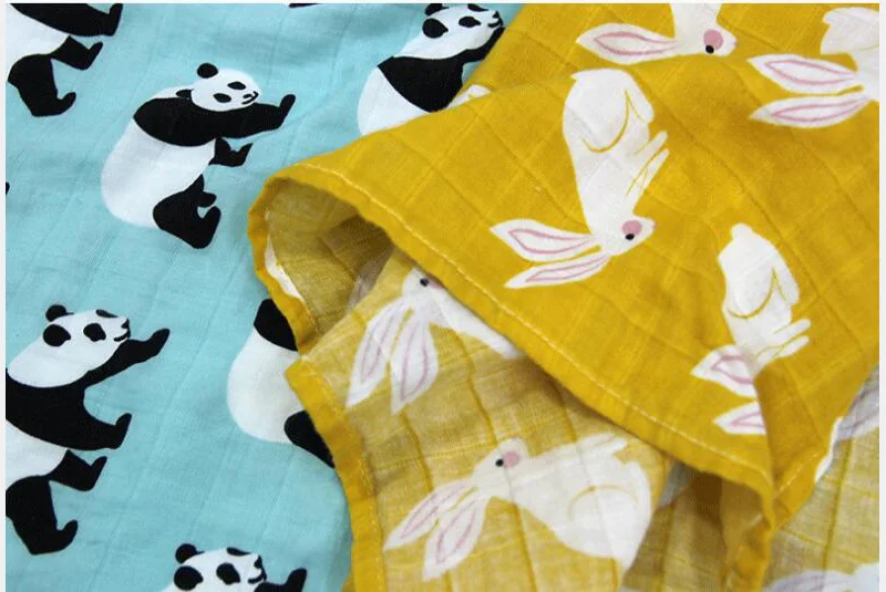 Dos piezas de tela con diferentes estampados. A la izquierda hay una tela con fondo azul con un estampado de osos panda en blanco y negro. A la derecha hay una tela con fondo amarillo con un estampado de conejitos rosas y blancos.