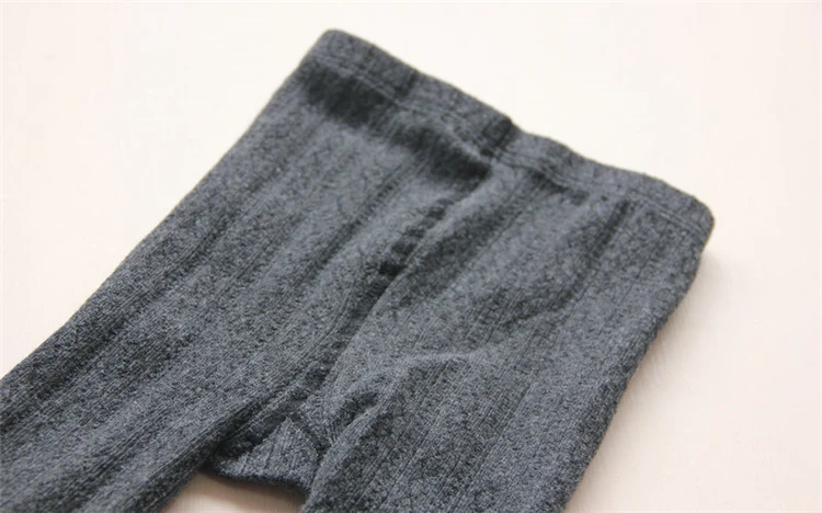 Un par de pantalones grises que se encuentran en una superficie blanca