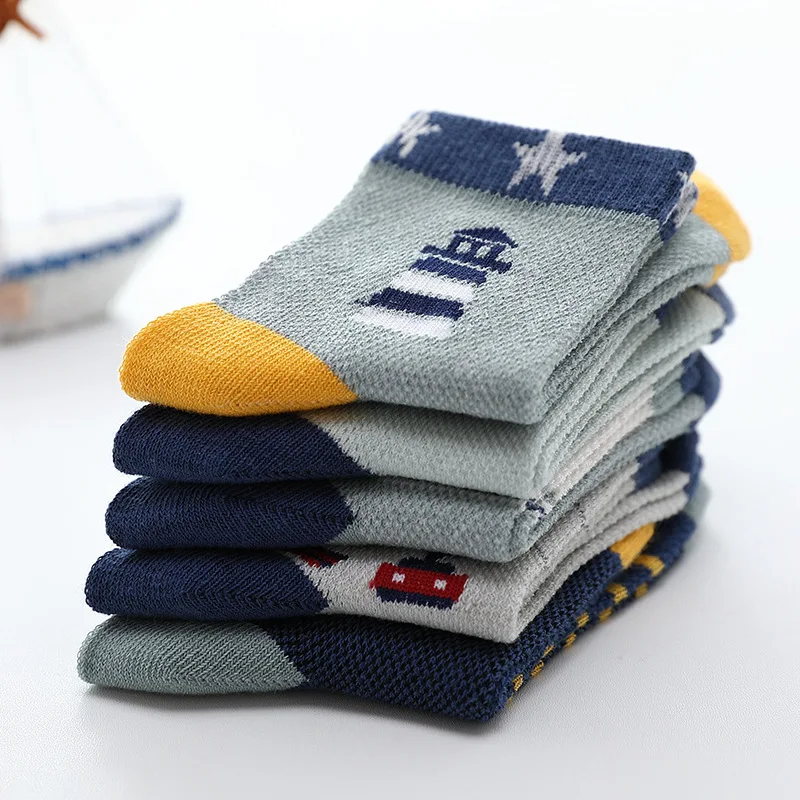Una pila de calcetines doblados. Los calcetines tienen un diseño colorido con varios patrones y colores, incluidos tonos de azul, amarillo y blanco. El calcetín superior tiene el gráfico de una casa, lo que sugiere que estos calcetines pueden tener un tema o estar diseñados para un propósito u ocasión específicos.