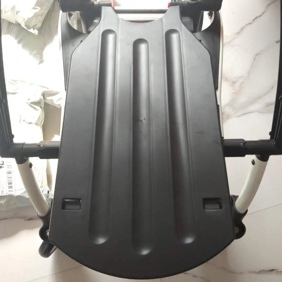 Un primer plano de un asiento negro, que parece ser parte de un mueble o equipo. El asiento tiene una superficie texturizada y está sujeto a una estructura que parece estar hecha de metal.