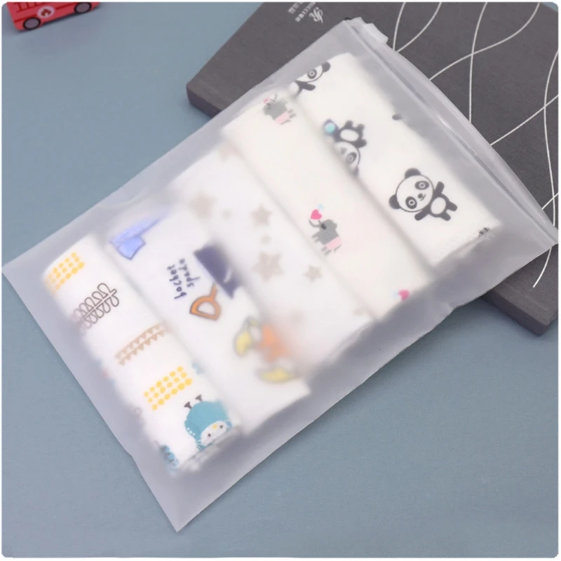 Una bolsa de plástico transparente que contiene lo que parece ser un juego de pañales para bebés. Los pañales tienen varios patrones y diseños, incluidos lo que parecen personajes de dibujos animados y posiblemente algún texto. La bolsa se coloca sobre una superficie con un libro y un pequeño carrito de juguete al fondo.