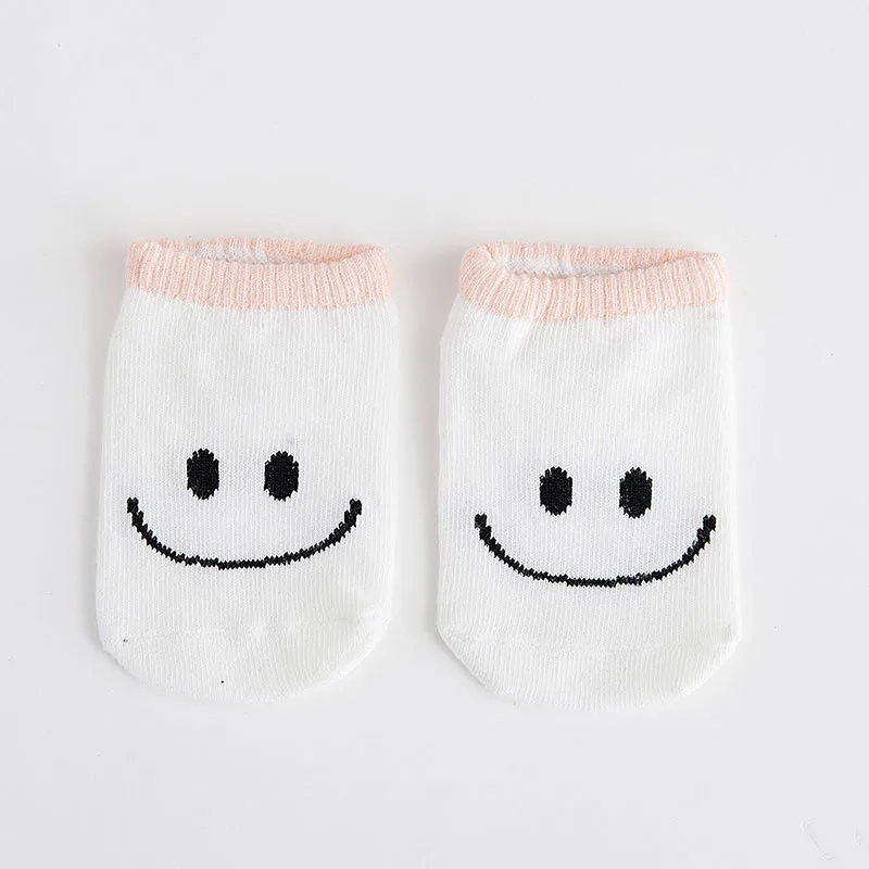 Dos pares de calcetines con un diseño de carita sonriente. Los calcetines son blancos con un ribete rosa en la parte superior y las caras están dibujadas en negro. Parecen calcetines infantiles por su talla y su divertido diseño.