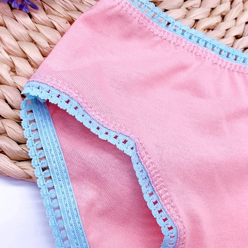 Una prenda de vestir, concretamente un pantalón corto o una falda, de color rosa claro o coral. La prenda tiene un ribete de encaje azul en el bajo y en el interior de la pierna, que le da un toque decorativo.