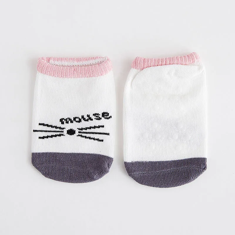 Un par de calcetines de bebé. Están diseñados con un lindo tema de ratón, con un gráfico de ratón en blanco y negro en la parte superior de los calcetines. Los calcetines tienen un ribete rosa en la parte superior y una banda gris en la parte inferior, lo que añade un toque de color a los calcetines que de otro modo serían blancos.