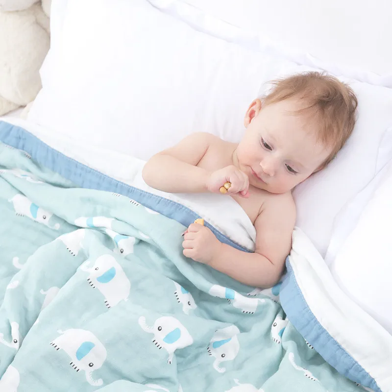Un bebé está acostado en la cama con una sábana blanca y una manta azul