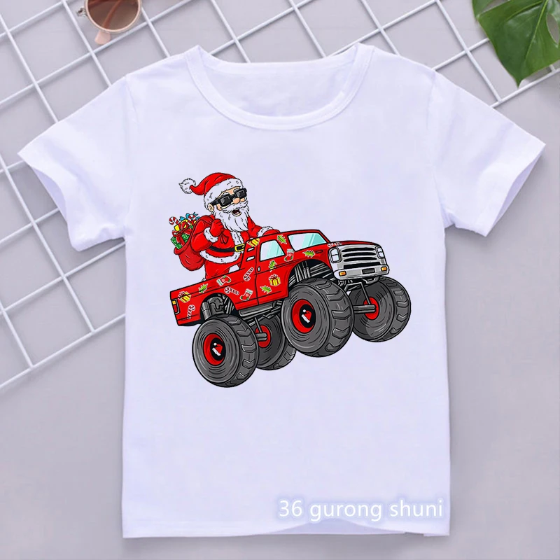 Una camiseta blanca con un diseño gráfico impreso. El diseño presenta una caricatura de Papá Noel sentado en el asiento del conductor de un camión monstruo rojo. Papá Noel lleva su tradicional traje rojo, sombrero y botas, y tiene un saco de regalos en su regazo.