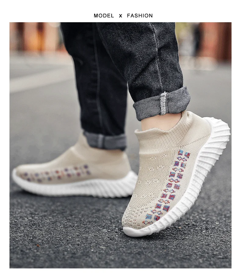 Persona que lleva un par de zapatillas deportivas con un diseño distintivo. Las zapatillas tienen un color base crema o beige con un patrón de cuadrados o mosaicos de colores a lo largo del costado. La persona también lleva pantalones oscuros con un puño enrollado para dejar al descubierto los tobillos, que es un estilo de moda común.