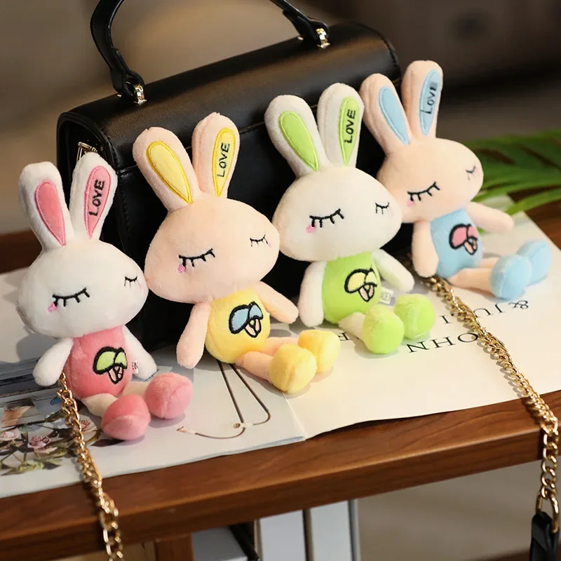 Una fila de conejitos de peluche se sienta en una mesa al lado de un bolso