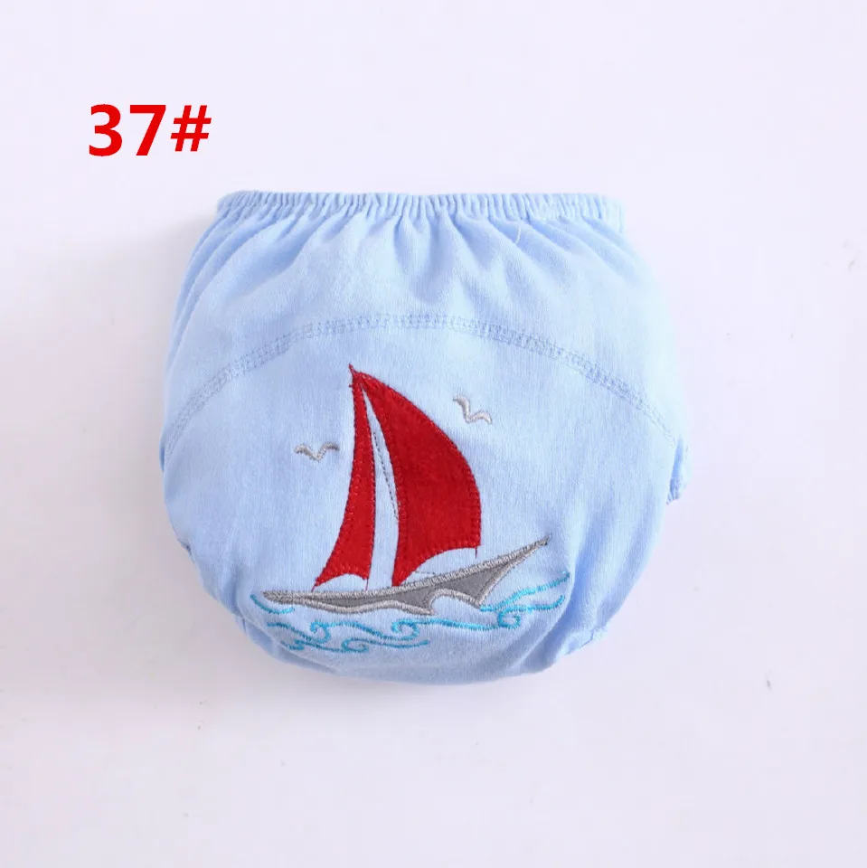 Un trozo de tela con un velero bordado. El velero tiene una vela roja y está representado sobre un fondo azul claro con un patrón de ondas azules.