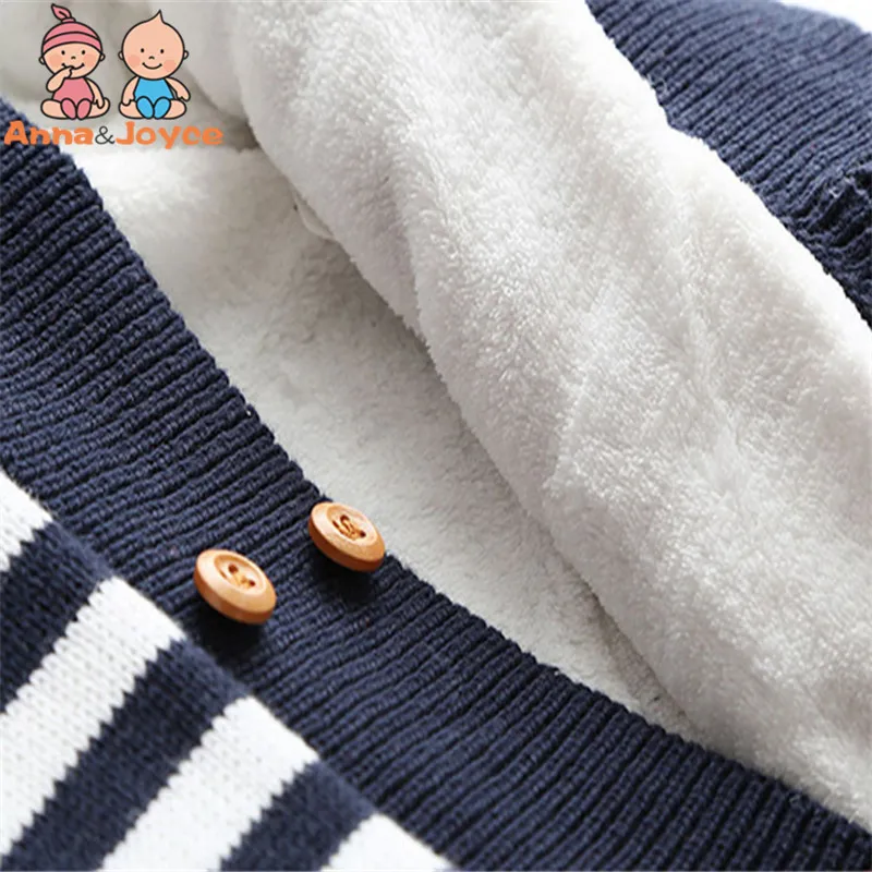 Un primer plano de una prenda de vestir, específicamente una sección de una prenda con puños acanalados. El brazalete parece ser azul marino con rayas blancas y tiene dos pequeños botones redondos de madera.