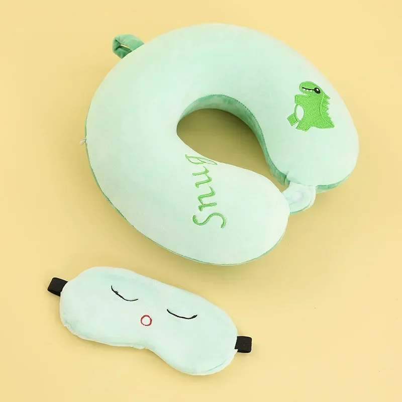Una almohada verde con un dinosaurio y una almohada blanca con una cara sonriente
