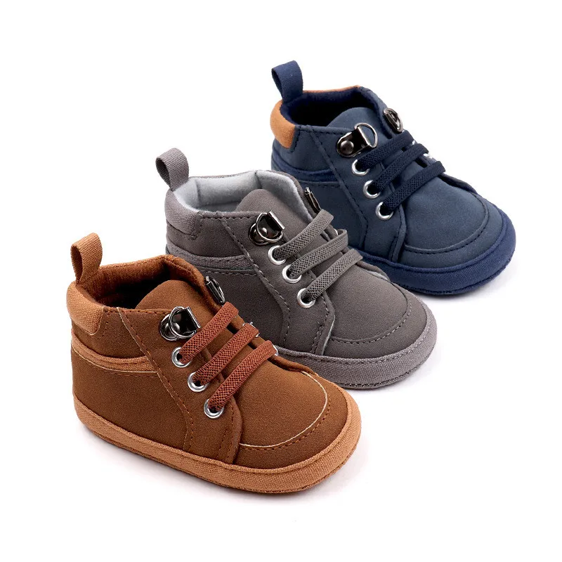 Dos zapatos para bebés un marrón y otro azul, tienen un fondo blanco.