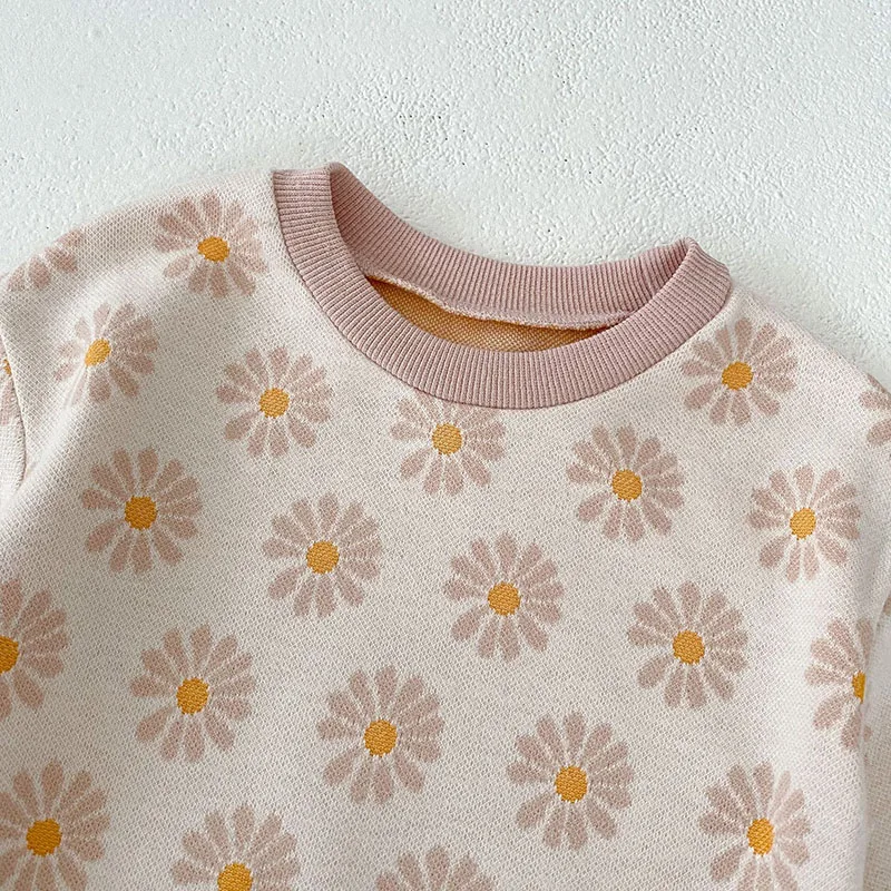 Un suéter blanco con un collar rosa y flores amarillas