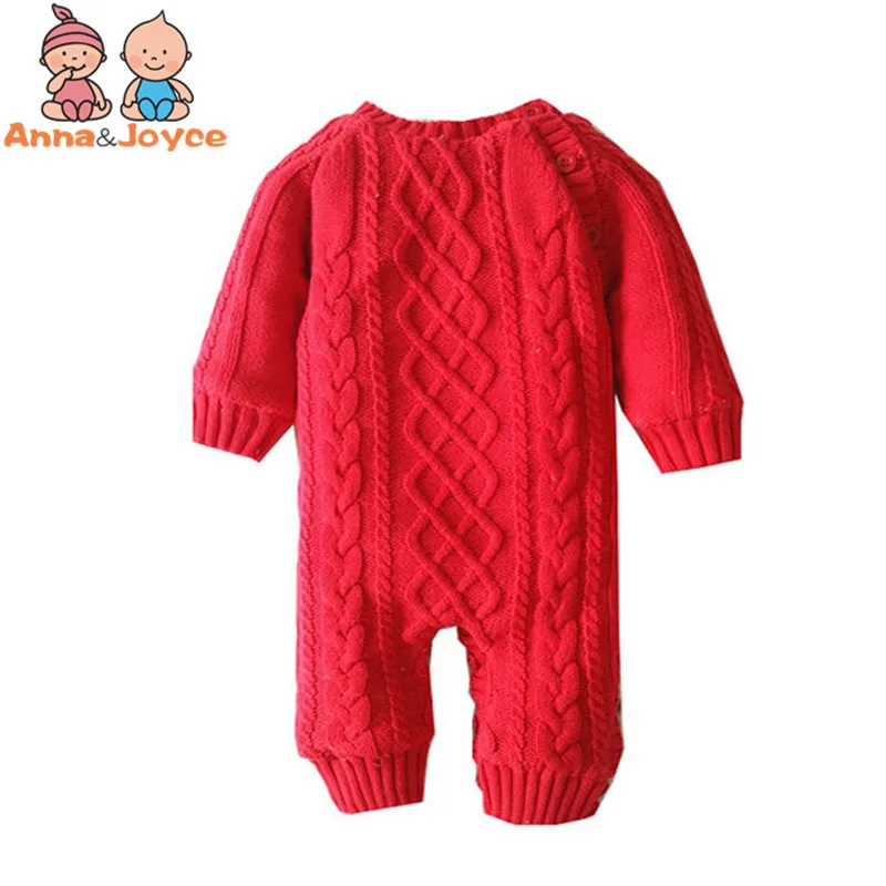 Un mono de punto rojo con un patrón de punto trenzado. Parece estar diseñado para un bebé o un niño pequeño, dado el tamaño y el estilo. El mono tiene mangas largas y un cuerpo largo, lo que sugiere que está destinado a mantener abrigado al usuario.