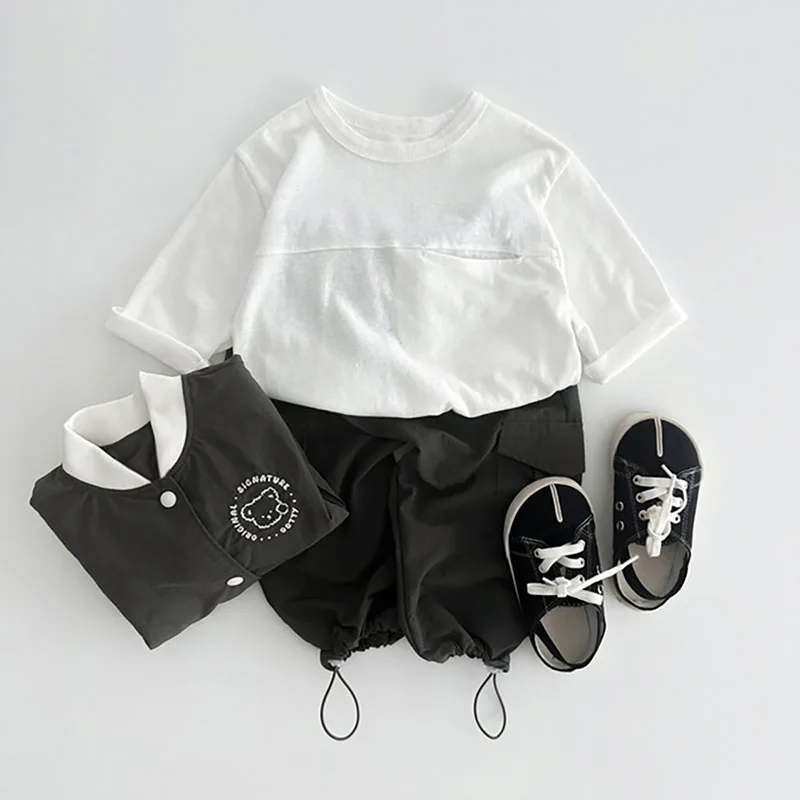 Una camisa blanca pantalones cortos negros y los zapatos tienen un fondo blanco