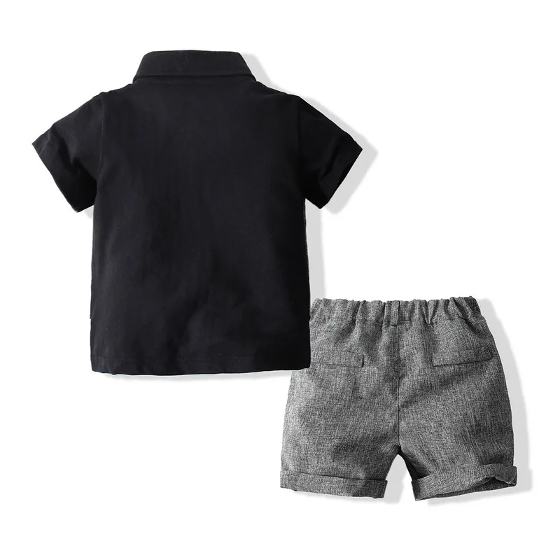 Se muestran una camisa negra y pantalones cortos grises sobre un fondo blanco.
