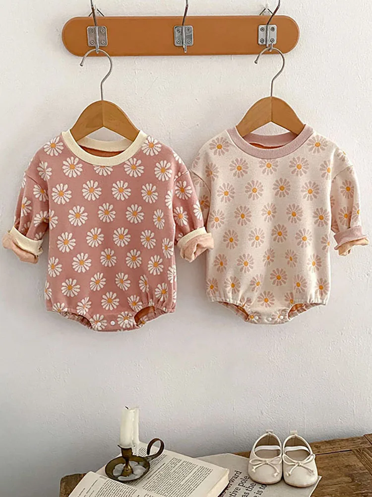 Dos ropa de bebé colgando de un estante