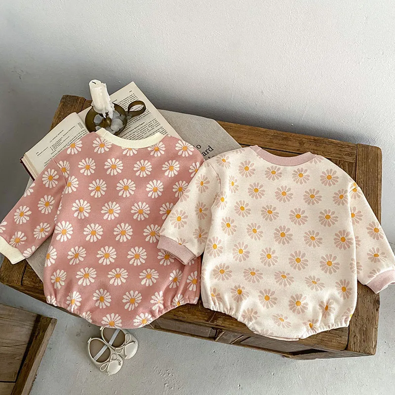 Dos camisas para bebés con flores sobre ellas