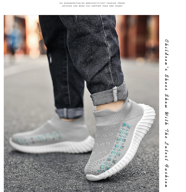 Persona que lleva un par de zapatillas deportivas con un diseño distintivo. Las zapatillas tienen un color base blanco con un patrón de puntos o motas azules y verdes en el lateral. La persona también lleva pantalones oscuros con un puño enrollado para dejar al descubierto las zapatillas.