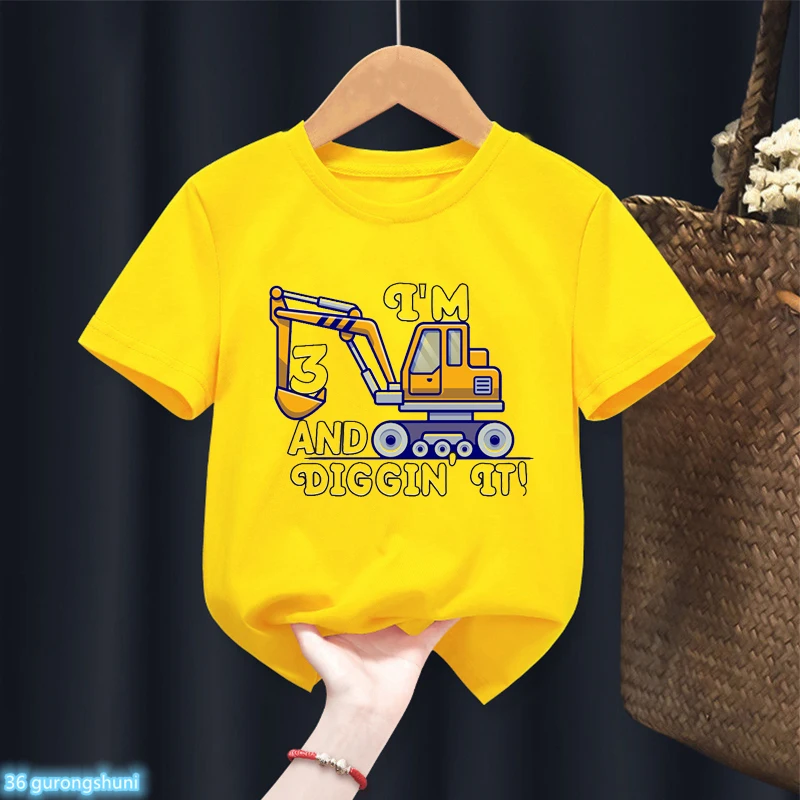 Una camiseta amarilla con un diseño gráfico. El diseño presenta una caricatura de un vehículo de construcción, que parece ser una grúa, con el número 3.