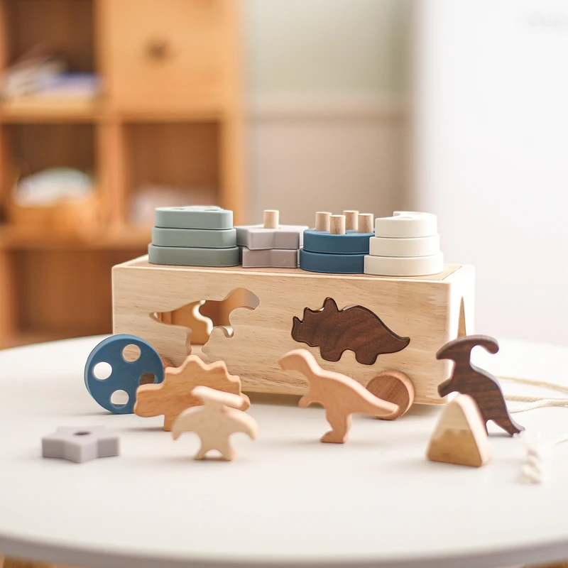 Una caja de juguetes de madera con dinosaurio y otros juguetes de animales