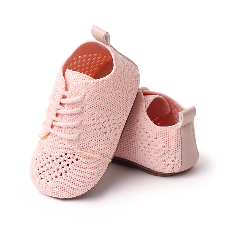 Un par de zapatos de bebé rosa con encaje blanco