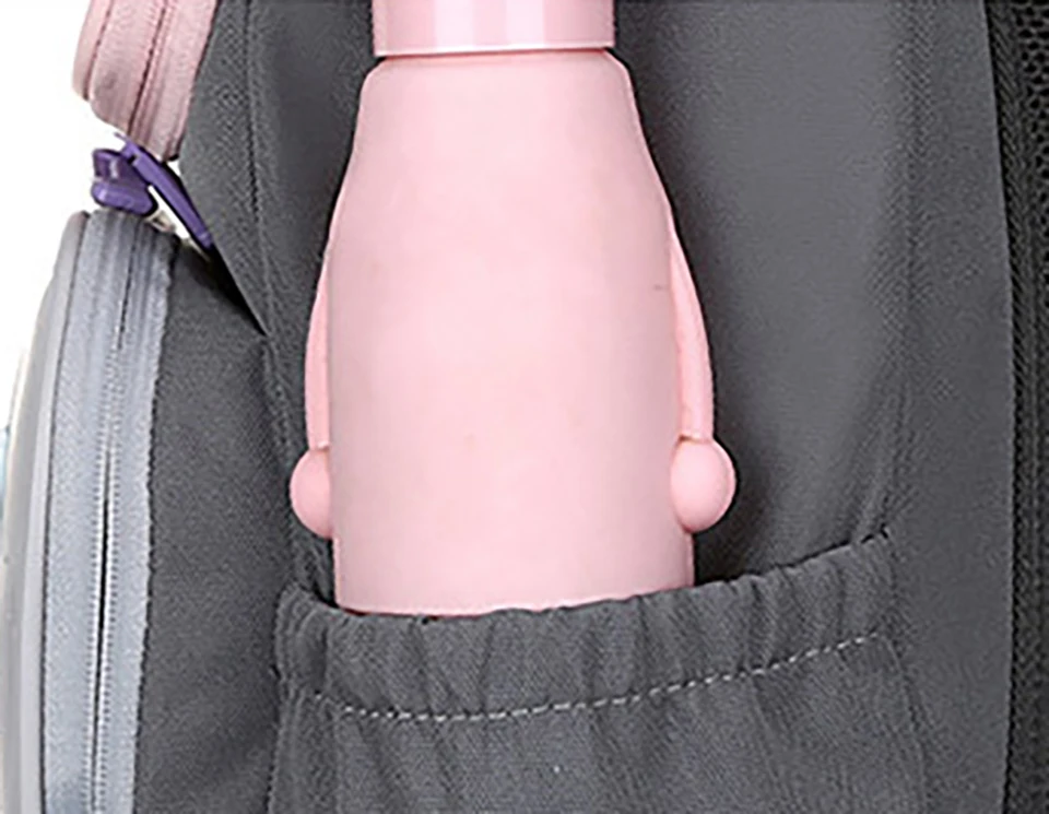 Un objeto rosa que parece ser una botella o recipiente de algún tipo, parcialmente insertado en el bolsillo de una mochila o bolso. La botella tiene una tapa y un asa, lo que sugiere que podría estar diseñada para transportarla fácilmente o para usarla en un contexto específico, como viajes o actividades al aire libre.