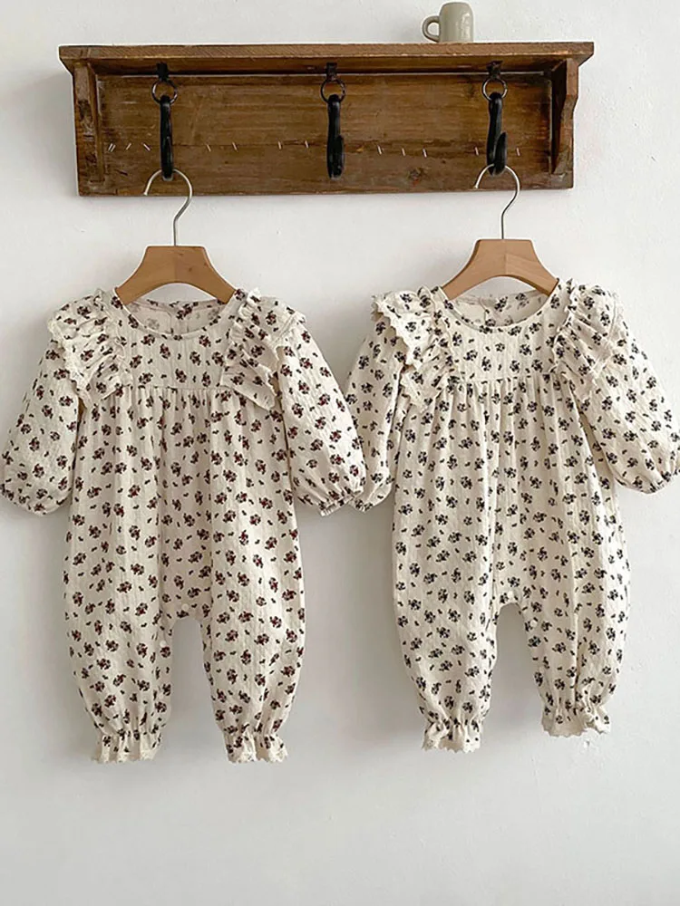 Dos atuendos para bebés colgando de una rejilla de madera