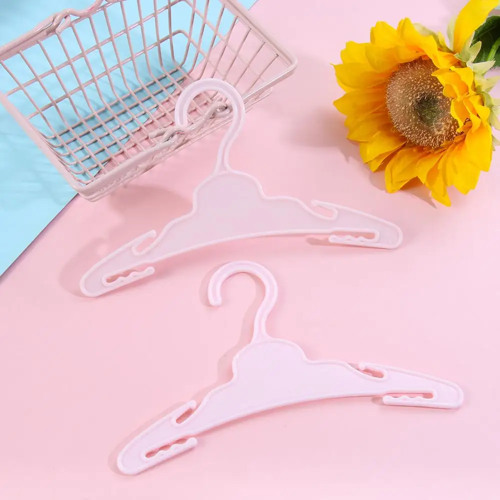 Dos perchas blancas sobre un fondo rosa