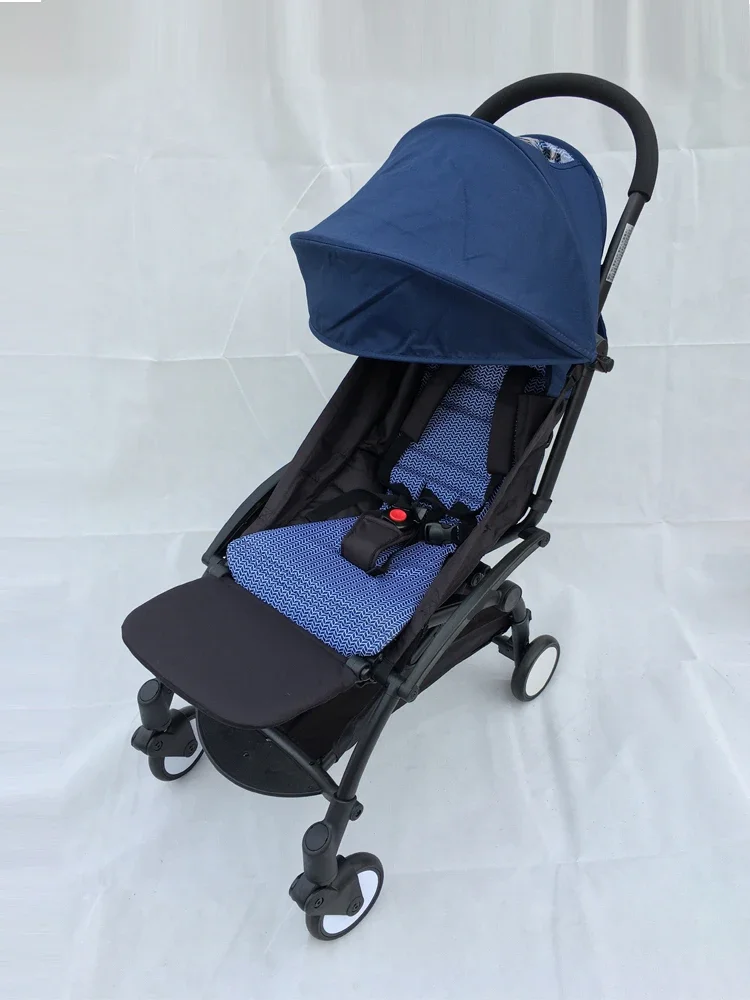 Un cochecito con capota azul y estructura negra. El cochecito parece estar diseñado para un niño pequeño, con un asiento acolchado y un reposapiés.