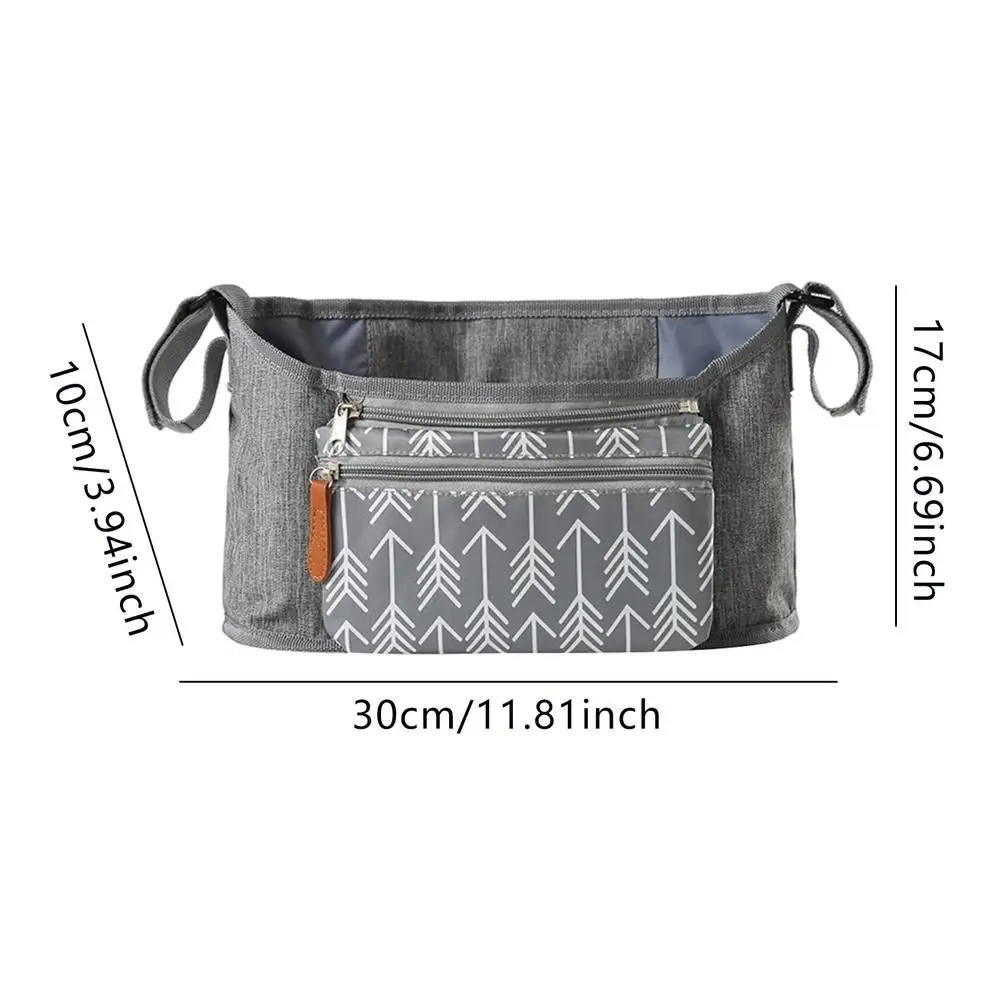 Un bolso bandolera pequeño con estampado geométrico. Parece ser un accesorio informal y liviano adecuado para llevar elementos esenciales como una billetera, llaves y un teléfono. El bolso tiene una correa para llevarlo cruzado y hay medidas en centímetros y pulgadas, que indican su tamaño.